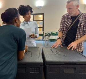 A man talking with a woman standing against cooler boxes in a pantry