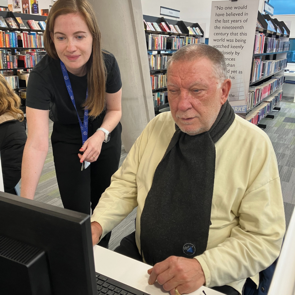 A man being taught how to use a computer with a teacher next to him